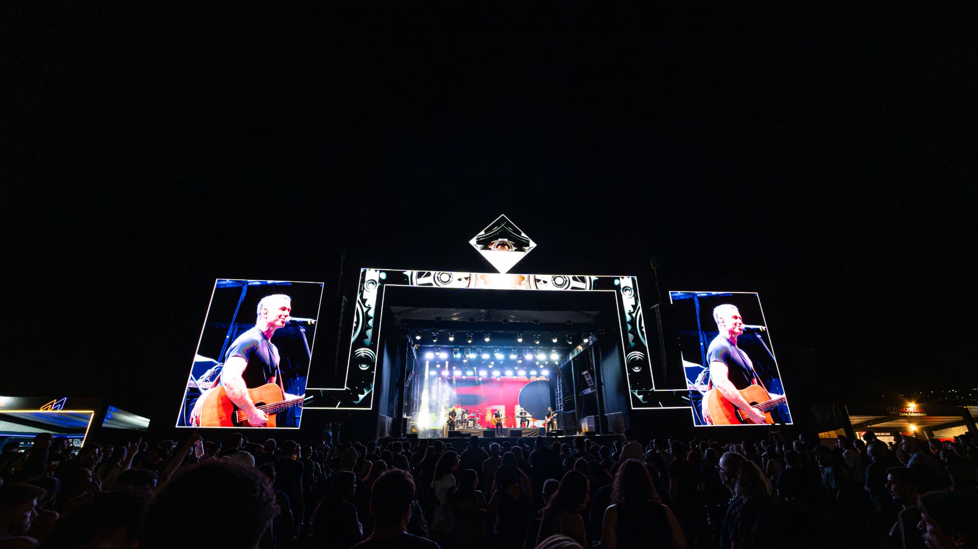 Palco do September Motofest iluminado à noite, com telões e público durante o show